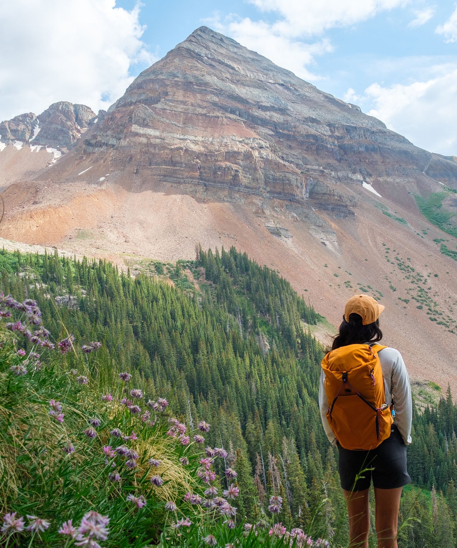 Woman standing with orange backpack looking at mountains